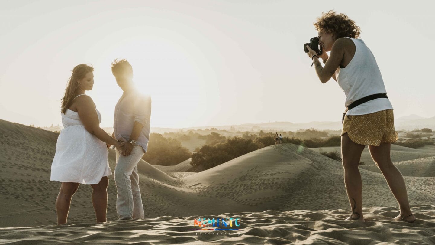 Fotógrafa retratando pareja en desierto de arena al atardecer