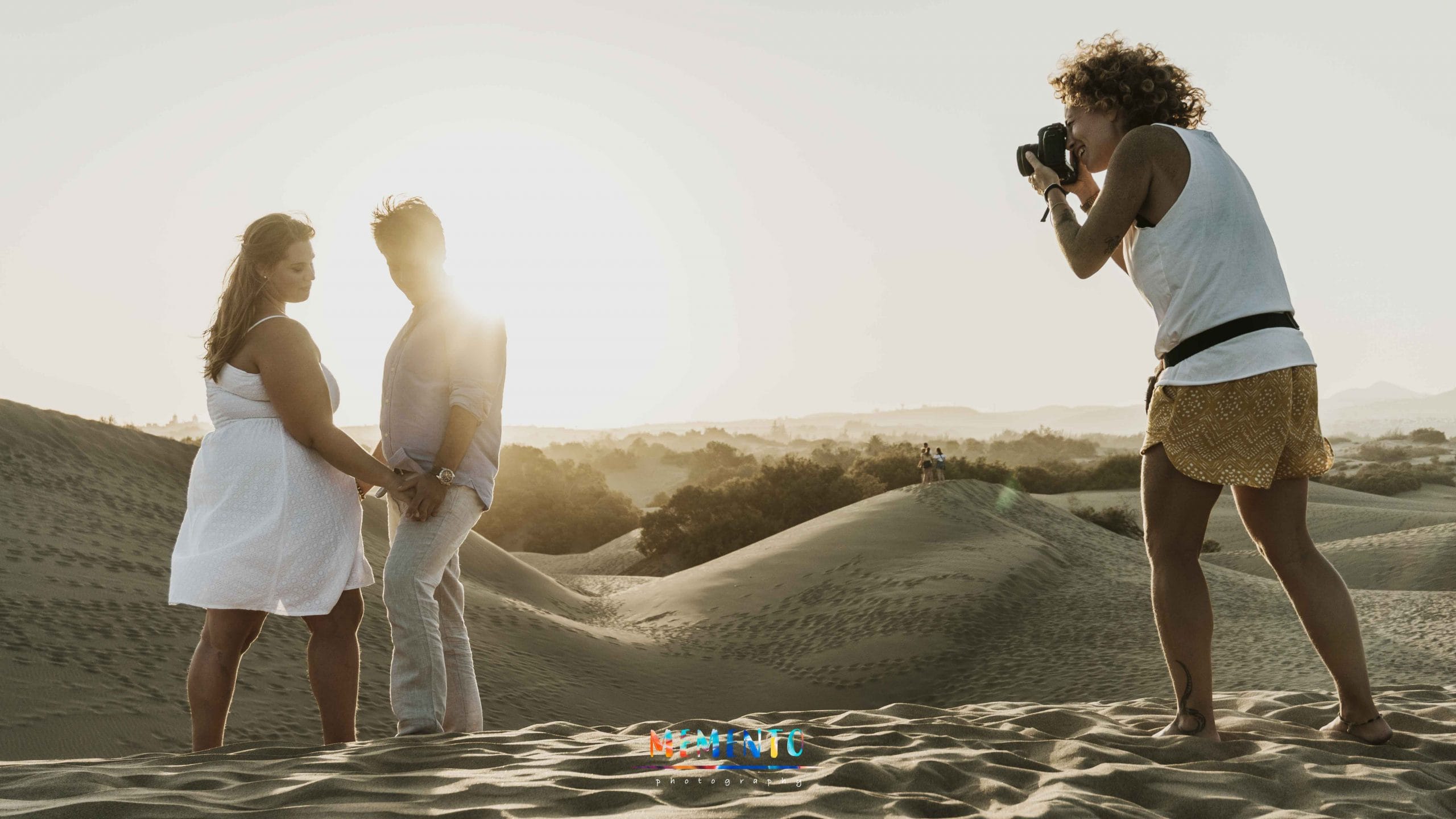 Fotógrafa retratando pareja en desierto de arena al atardecer