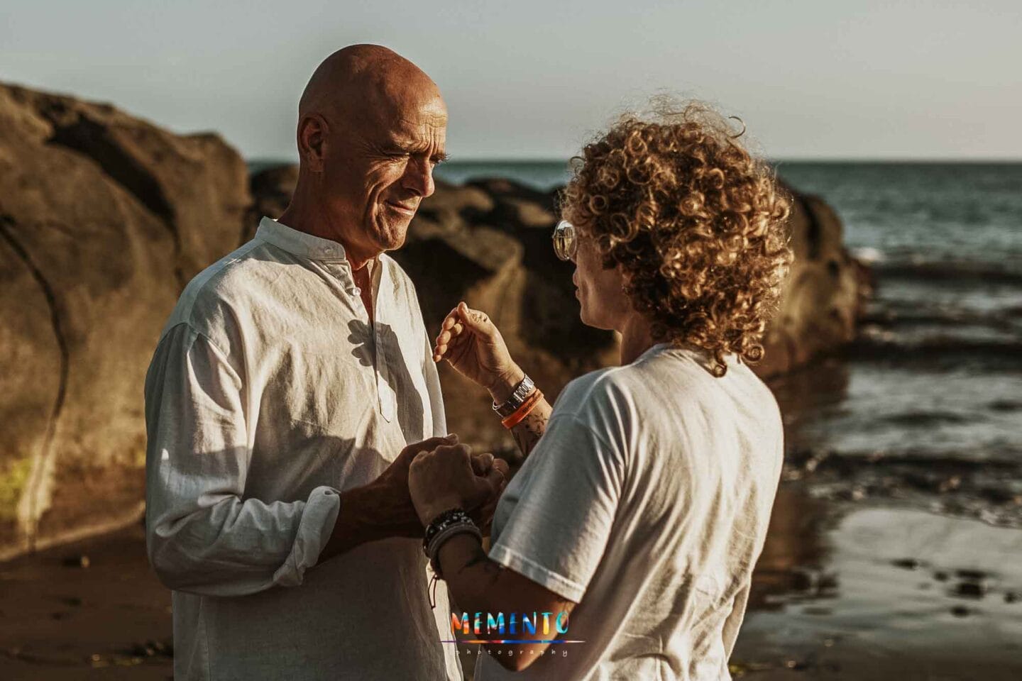 Pareja adulta conversando en playa rocosa junto al mar