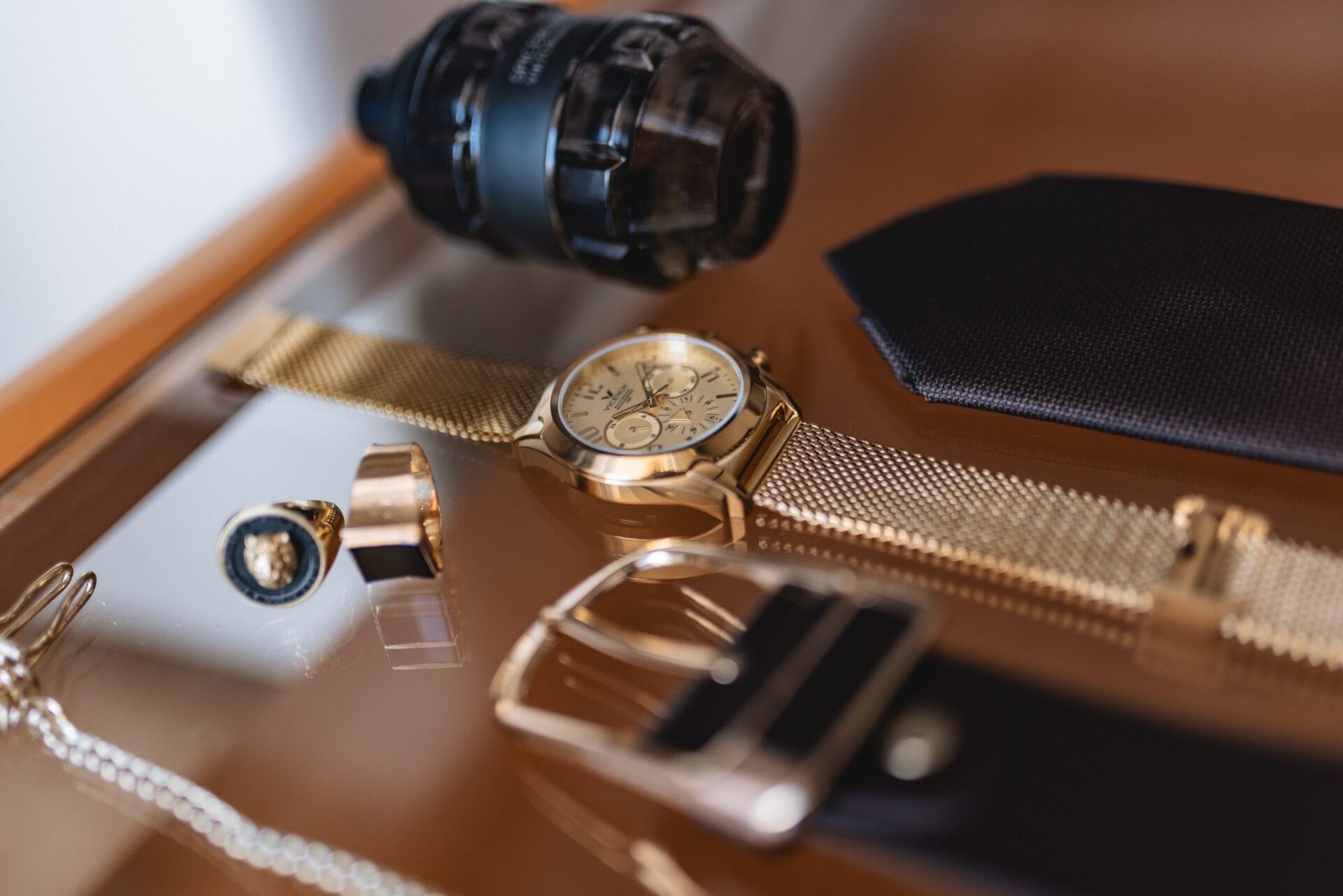 Reloj de oro, gemelos y accesorios elegantes sobre madera