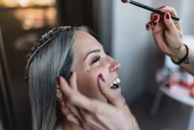 Maquilladora aplicando maquillaje con pincel a mujer sonriente