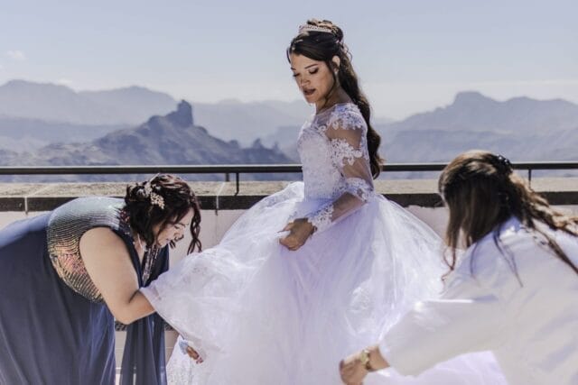 Novia con vestido blanco rodeada de damas en montañas