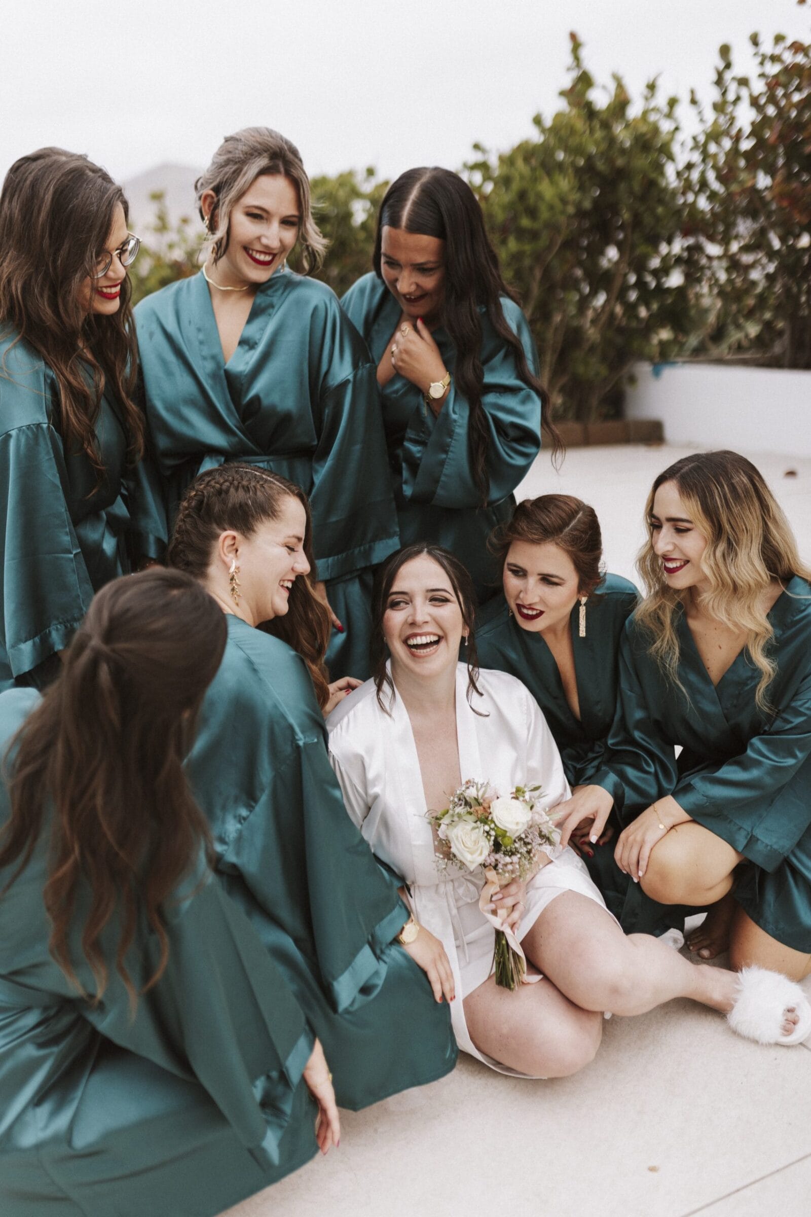 Novia sonriente rodeada de damas de honor en bata turquesa