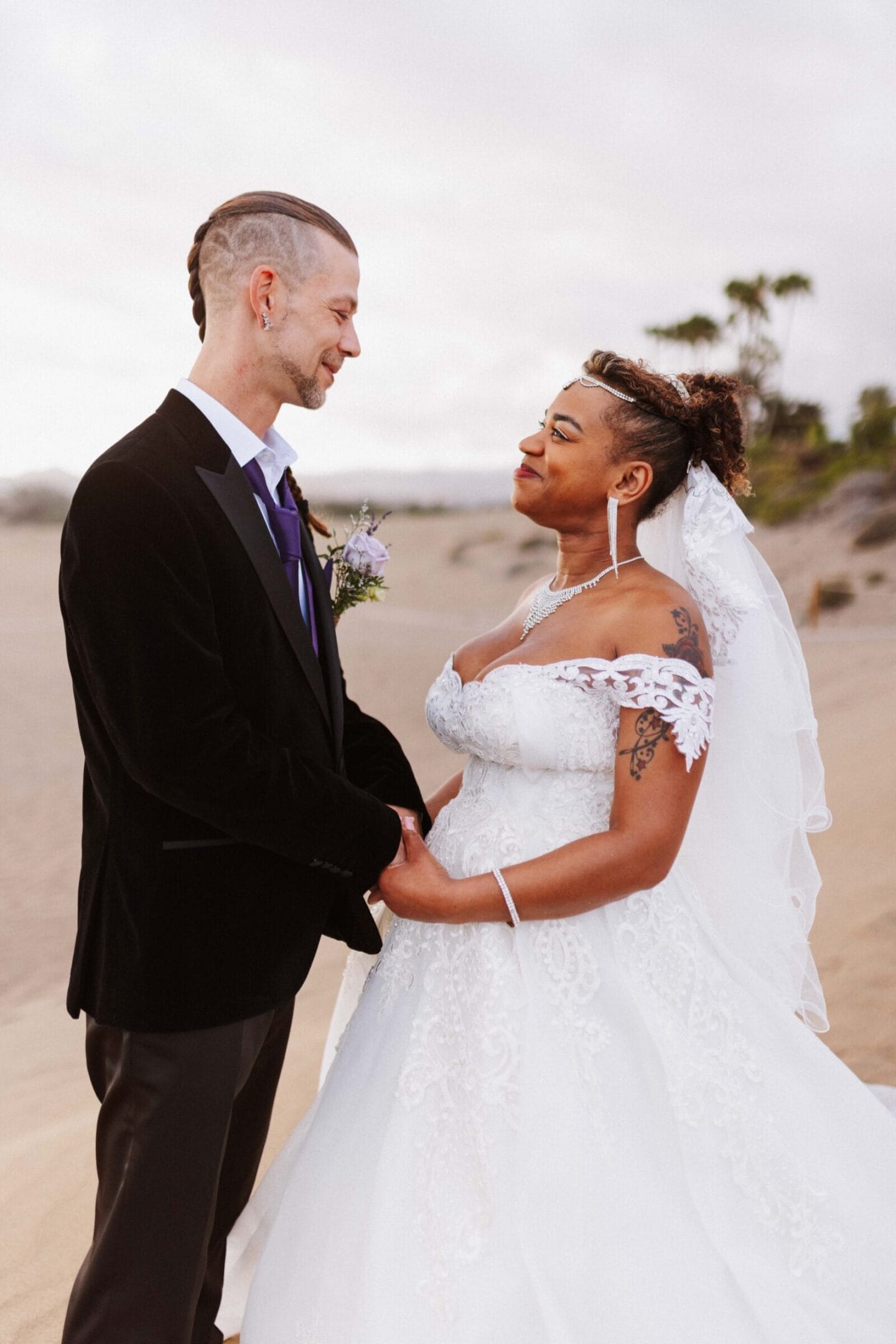 Pareja de novios sonriendo en playa durante ceremonia boda