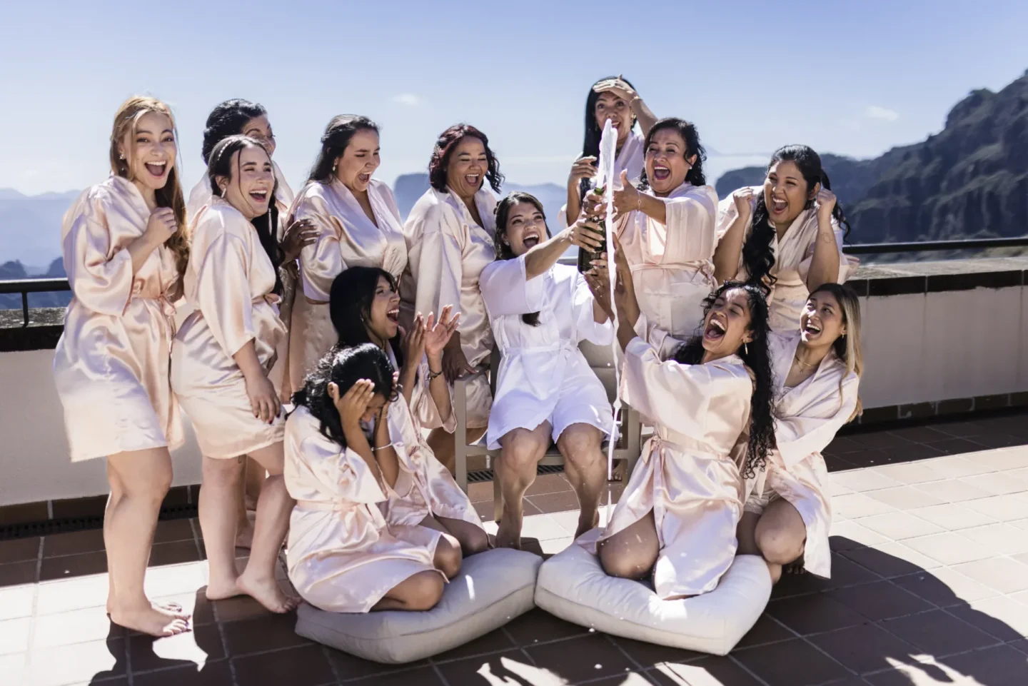 Grupo de mujeres celebrando en bata blanca con vistas montañosas